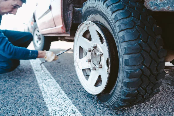 El hombre cambia la rueda manualmente en un camión todoterreno 4x4 — Foto de Stock