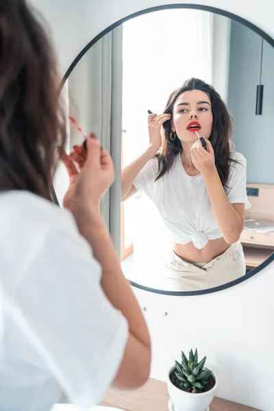 Jeune femme appliquant rouge à lèvres regardant miroir — Photo