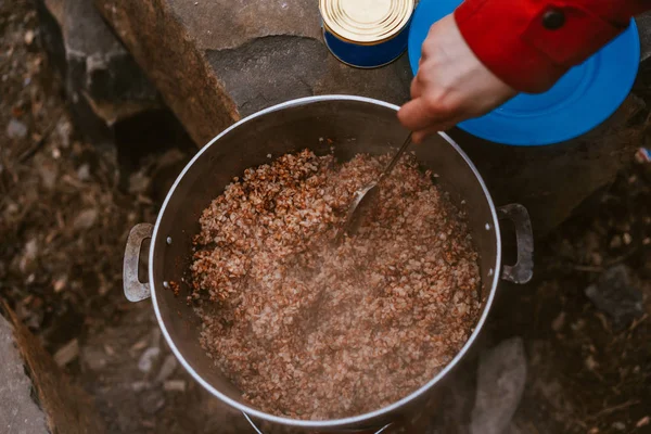 Camper připravuje jídlo ve velké konvici na táborním ohni — Stock fotografie