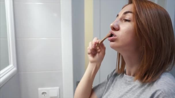 Красивая молодая женщина в ванной чистит зубы — стоковое видео