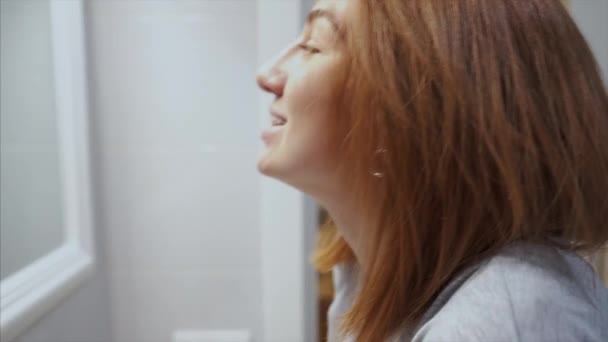 Гарненька молода жінка у ванній чистить зуби — стокове відео