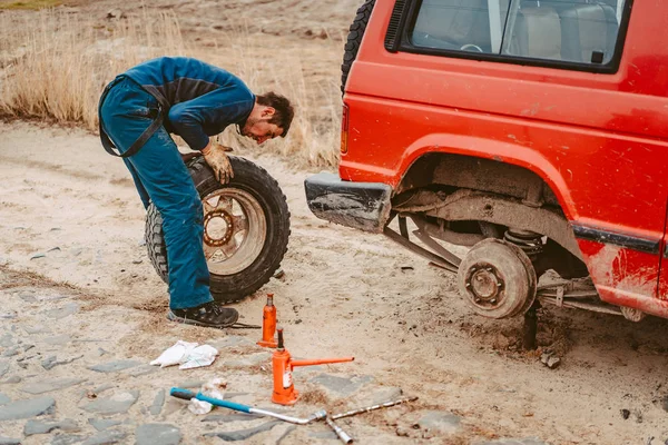 Чоловік міняє колесо вручну на 4x4 поза вантажівкою — стокове фото