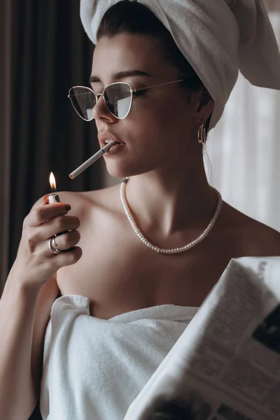 Belle jeune femme dans une serviette fume une cigarette et lit le journal — Photo