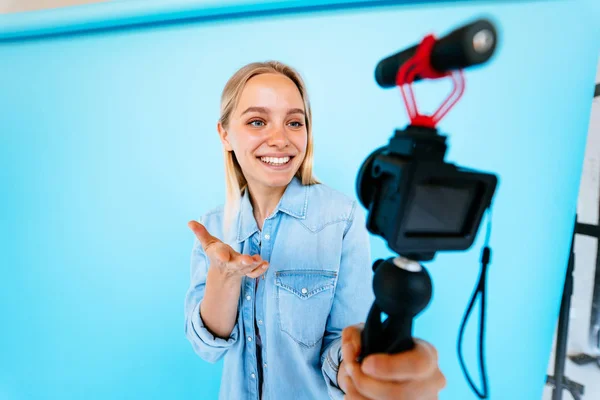Vacker flicka bloggare lindrar sig själv vid kameran isolerad blå bakgrund — Stockfoto