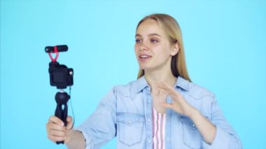 Güzel kız blogcu kendini mavi arkaplanda rahatlatıyor