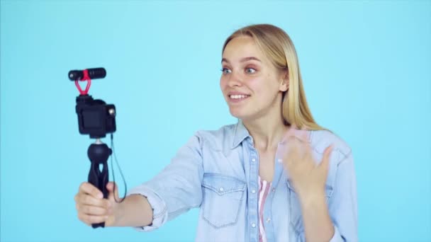 Mooi meisje blogger verlicht zichzelf op camera geïsoleerde blauw achtergrond — Stockvideo