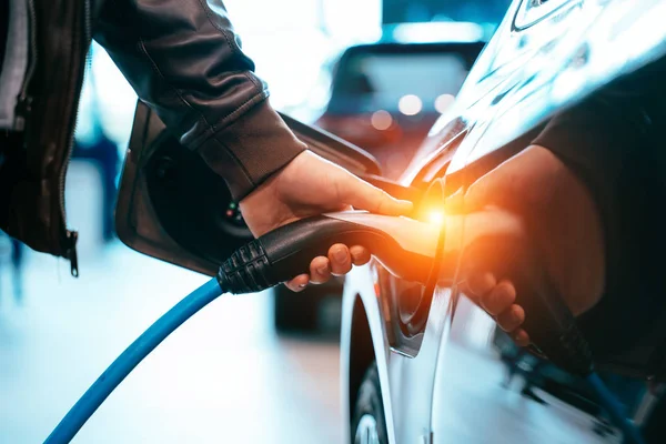 人間の手は電気自動車に接続する電気自動車を保持しています ロイヤリティフリーのストック画像