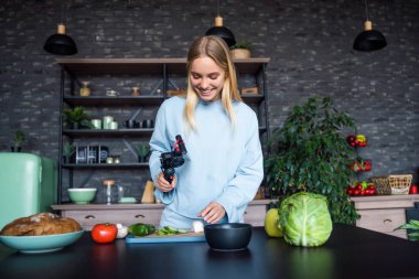 Genç ve güzel sarışın mutfakta yemek pişirirken videolar çekiyor.