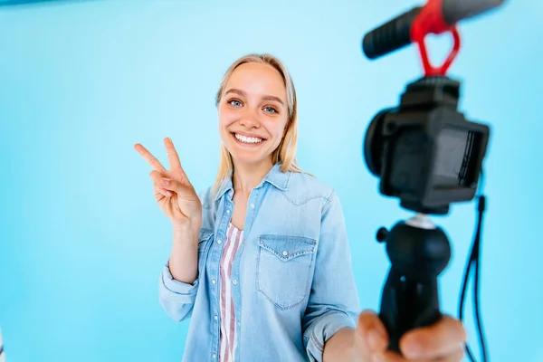 Hermosa chica blogger se alivia a sí misma en la cámara aislado fondo azul — Foto de Stock