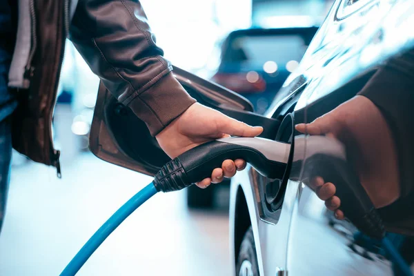 A mão humana está segurando o carregamento do carro elétrico conecte ao carro elétrico — Fotografia de Stock