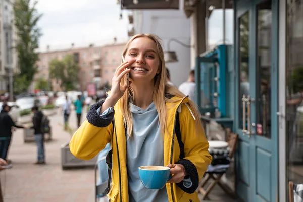 Enchanteur jeune femme blonde avec smartphone tandis que dans la rue — Photo