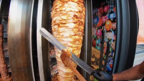 Um cozinheiro corta carne para fazer shawarma, giroscópios, doner kebab. — Vídeo de Stock