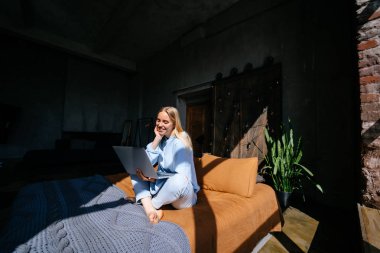 Gülümseyen çekici kadın yatakta laptop kullanarak yatıyor