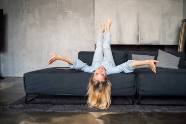 Başı baş aşağı kanepede eğlenen kadın.