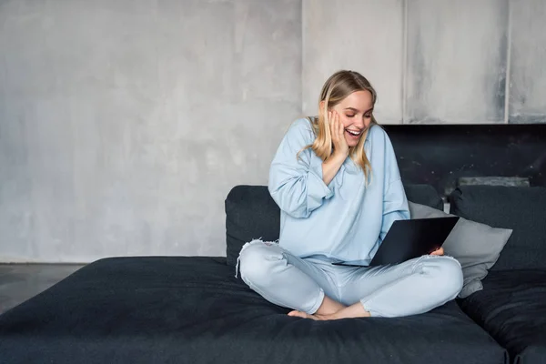 Immagine di donna felice che usa il computer portatile d'argento mentre si siede sul divano — Foto Stock