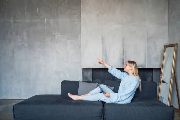 Bild einer glücklichen Frau mit silbernem Laptop, während sie auf dem Sofa sitzt — Stockfoto