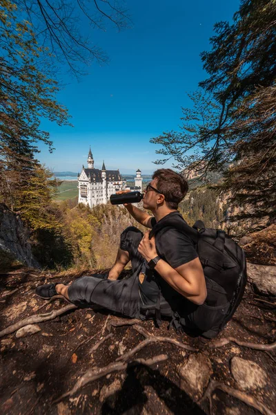 Ο τύπος πίνει νερό στο κάστρο του λόφου στο παρασκήνιο — Φωτογραφία Αρχείου