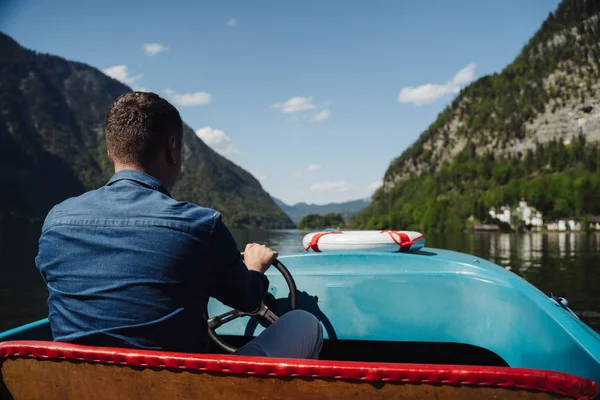 Snygg ung kille styr en motorbåt på en fjällsjö — Stockfoto