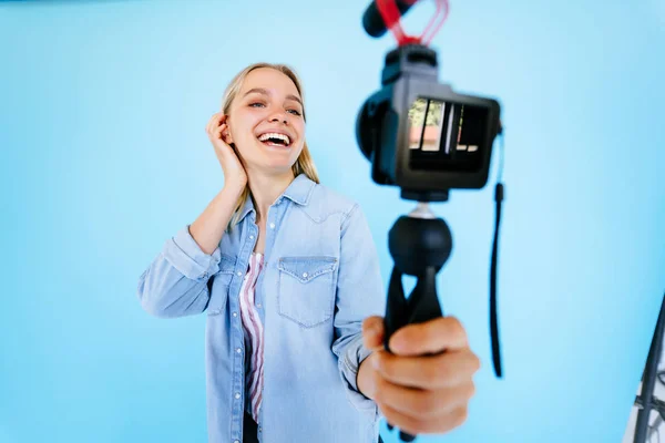 Menina bonita blogger alivia-se na câmera isolado fundo azul — Fotografia de Stock