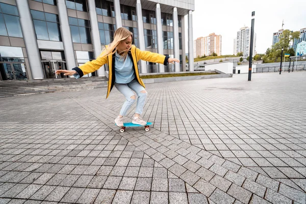 Femme blonde hipster femme chevauchant sur le longboard dans la rue à la ville. — Photo