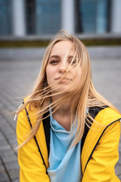 Linda jovem loira na rua, posando com vento no cabelo — Fotografia de Stock