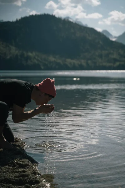 Ein Mann wäscht sich am Ufer eines Waldsees die Hände — Stockfoto