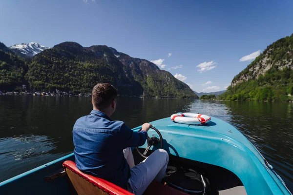 Yakışıklı genç adam bir dağ gölünde motorlu tekne kontrol ediyor. — Stok fotoğraf