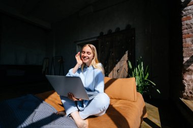 Gülümseyen çekici kadın yatakta laptop kullanarak yatıyor