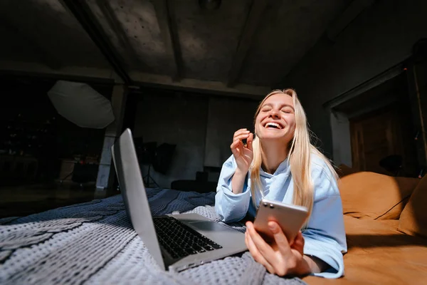 Akıllı telefon ile konuşurken yatakta yatan gülümseyen çekici kadın — Stok fotoğraf