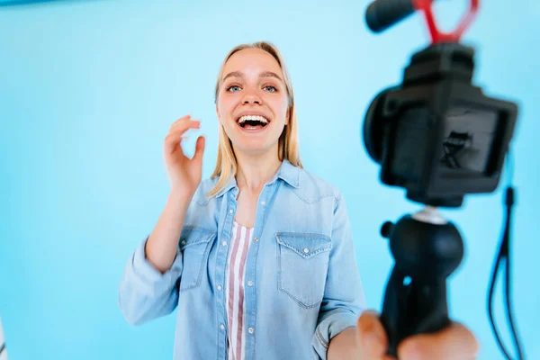 Menina bonita blogger alivia-se na câmera isolado fundo azul — Fotografia de Stock