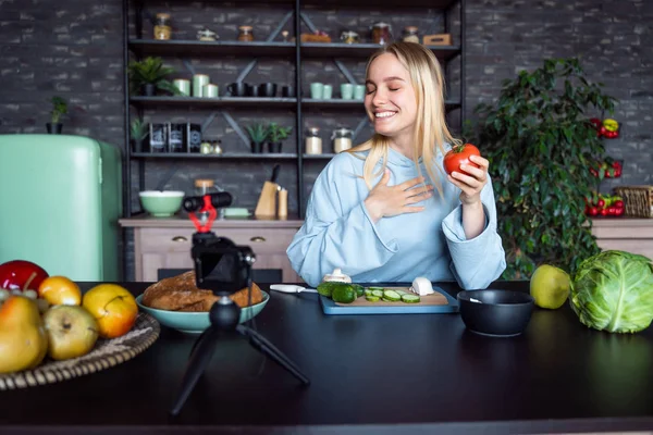 Genç ve güzel sarışın mutfakta yemek pişirirken videolar çekiyor.