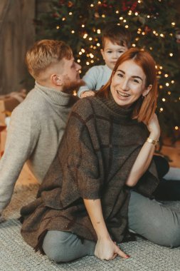 Genç Kafkasyalı anne baba oğul şömine ağacının yanında.