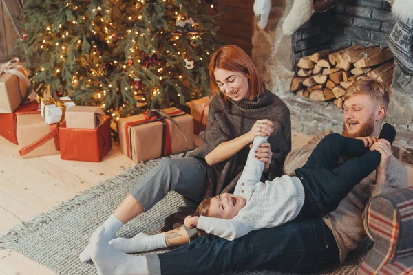 Ung kaukasisk familj mamma pappa son nära öppen spis julgran — Stockfoto