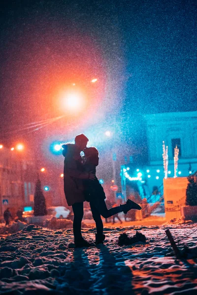 Fiatal felnőtt pár egymás karjaiban a hófödte utcán. — Stock Fotó