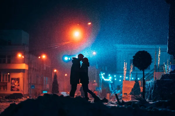 Young adult couple in each others arms on snow covered street. — ストック写真