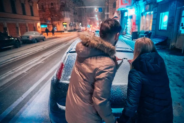 Νεαρό ζευγάρι ενηλίκων αντλεί μια καρδιά στο χιόνι που καλύπτονται αυτοκίνητο — Φωτογραφία Αρχείου