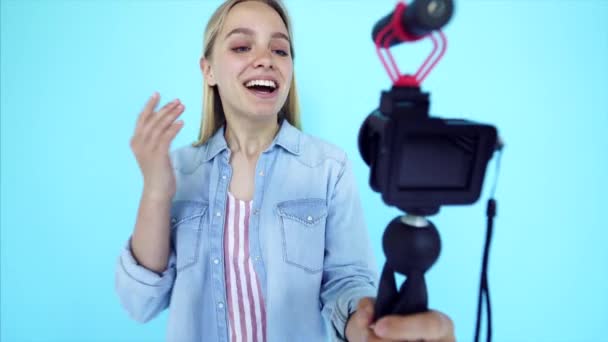 Hermosa chica blogger se alivia a sí misma en la cámara aislado fondo azul — Vídeo de stock