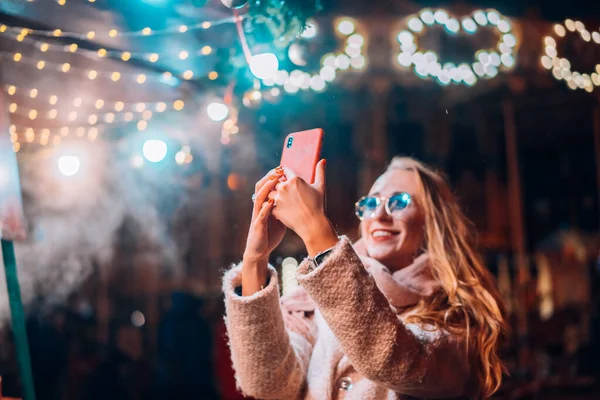 Woman takes selfie on defocus background light in evening street — ストック写真