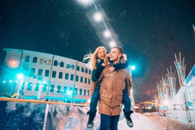 Sıcak kış kıyafetleri içinde neşeli ve neşeli bir çift etrafta oynaşıyor.