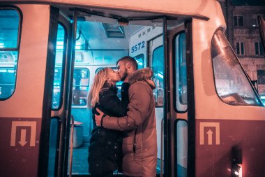 Kız ve erkek tramvayda öpüşürler.