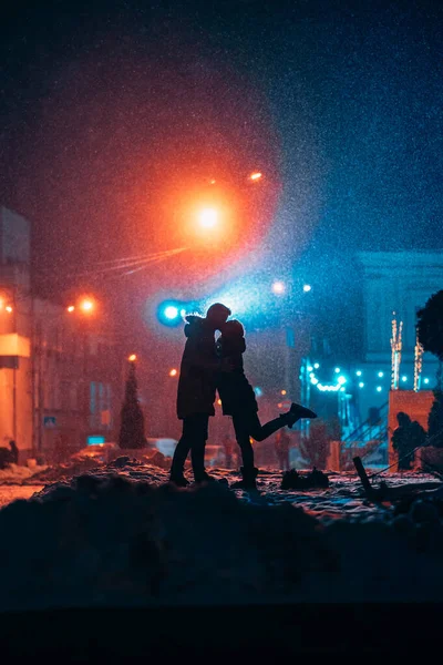 Jovem casal adulto em cada outros braços na neve coberta de rua . — Fotografia de Stock