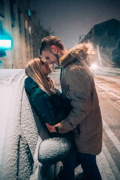Молода доросла пара цілується один з одним на засніженій вулиці — стокове фото