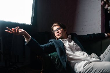 Çekici bir gencin yakın plan portresi kanepede dinleniyor.