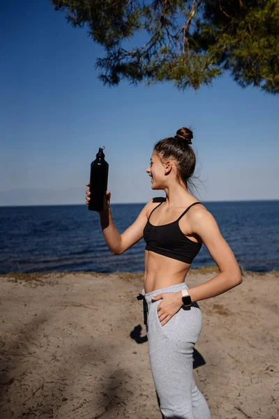 Mujer joven delgada bebiendo agua después del entrenamiento — Foto de Stock