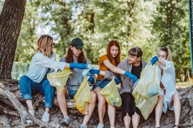 Bir grup aktivist arkadaş parkta plastik atık topluyor. Çevresel koruma.