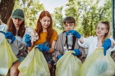 Bir grup aktivist arkadaş parkta plastik atık topluyor. Çevresel koruma.