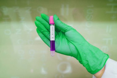 A rubber-gloved hand holds one test tube with coronavirus clipart