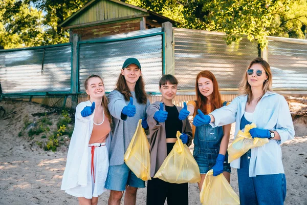 Группа друзей активистов собирает пластиковые отходы на пляже. Парни показывают большой палец вверх . — стоковое фото