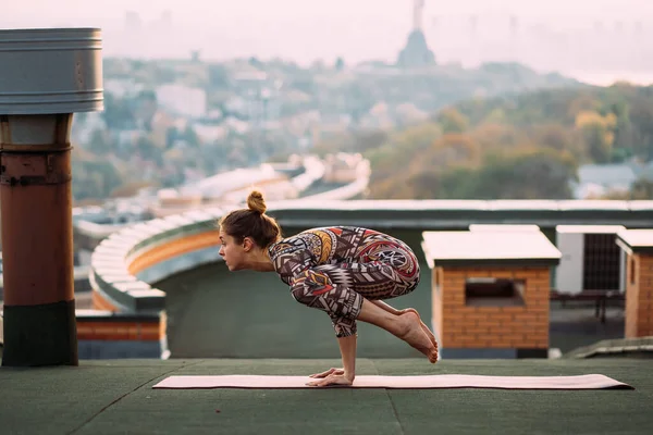 Mujer haciendo yoga en el techo de un rascacielos en la gran ciudad . —  Fotos de Stock