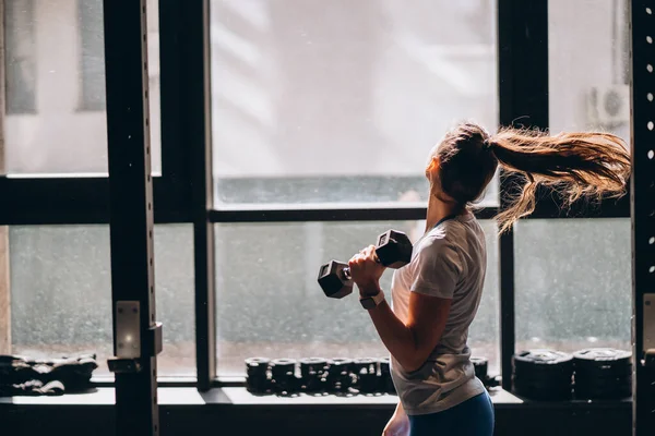 Gadis atletik yang ramping melakukan latihan fisik dengan dumbbells. — Stok Foto